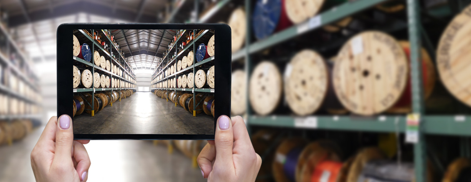 Ipad showing image of warehouse stocked with reels of wire and cable